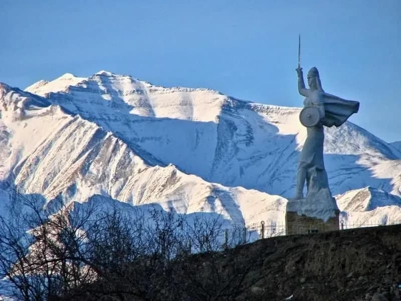 Памятник Парту Патиме у въезда в Кумух на фоне заснеженного горного хребта